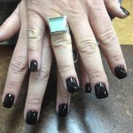 A woman's hands with black nails and a ring on them.