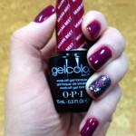 A woman's hand holding a gel polish in a burgundy color.