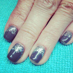 A woman's hand with grey and silver glitter nails.