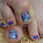 A woman's toe nails with blue and white designs.