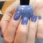 A woman holding a bottle of zoya nail polish.