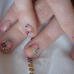 A woman's nails are decorated with flowers and butterflies.