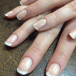 A woman's hands with white and beige nails.