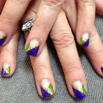 A woman's nails with purple, green and gold designs.