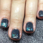 A woman's hand with black and blue glitter on it.