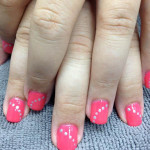 A girl's pink nails with white dots on them.