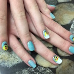 A woman's hand with blue and yellow nail designs.