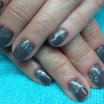 A woman's hand with grey and silver glitter nails.