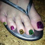 A woman's toe nails with colorful designs on them.