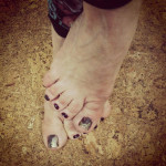 A person's toes with black nail polish.