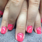 A girl's pink nails with white dots on them.