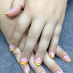 A woman's hands with yellow and white nails.