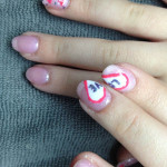 A woman's pink and white nails with hearts on them.