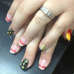 A woman's hand with a red, yellow, and black nail design.