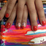 A woman's hand with a red and orange nail polish.