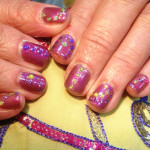 A woman's hand with a purple and gold manicure.