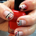 A person holding a red nail polish with black and white designs.