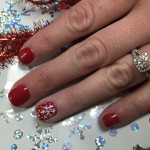 A woman with red nails and a christmas ring.