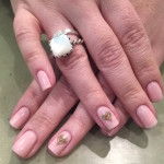 A woman's hands with pink nails and a gold ring.