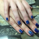 A woman's hands with blue nail polish on them.