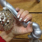 A hand holding a silver christmas ornament.