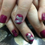 A woman's hands with purple and silver nail designs.