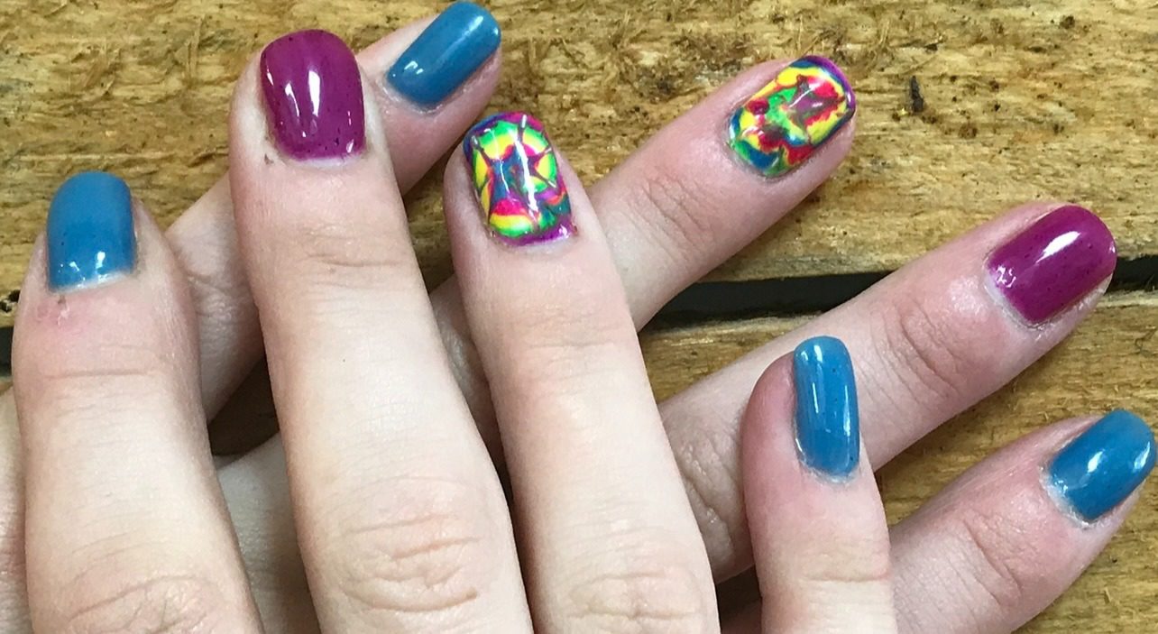 A close up of two fingers with different colored nails