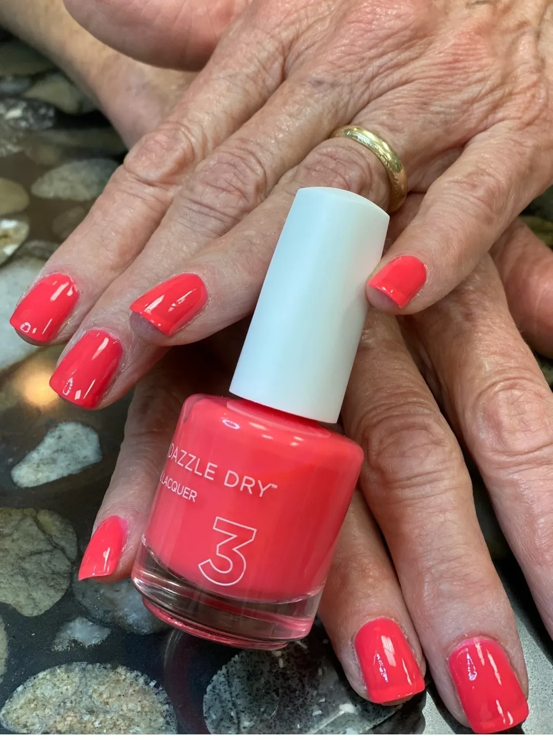 A woman is holding her nails with a nail polish bottle.