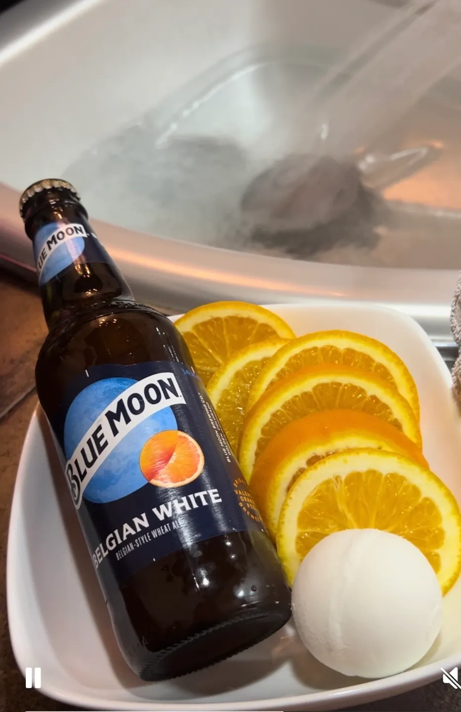 A bottle of beer and oranges on a plate.