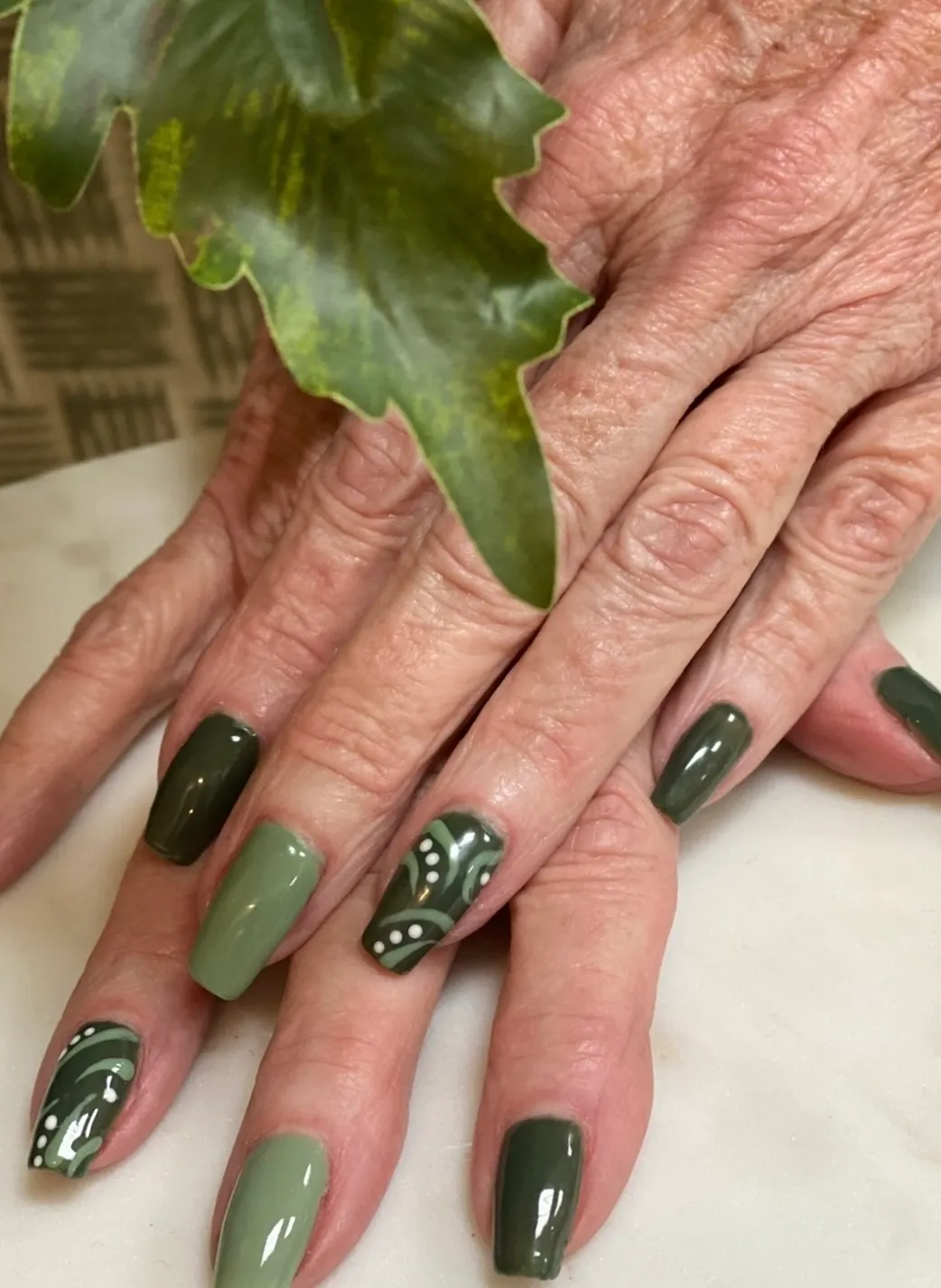 A person with green nails and some leaves