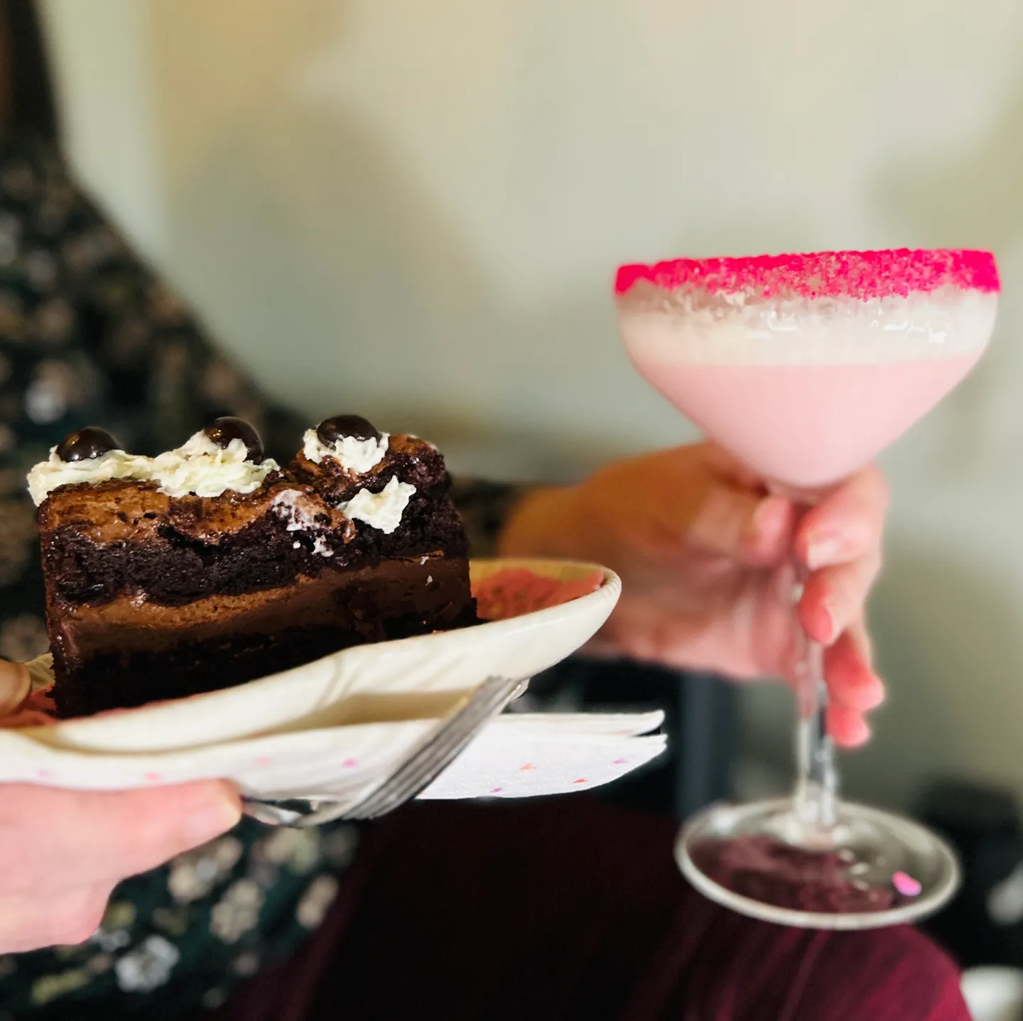 A person holding a plate with cake and a drink.