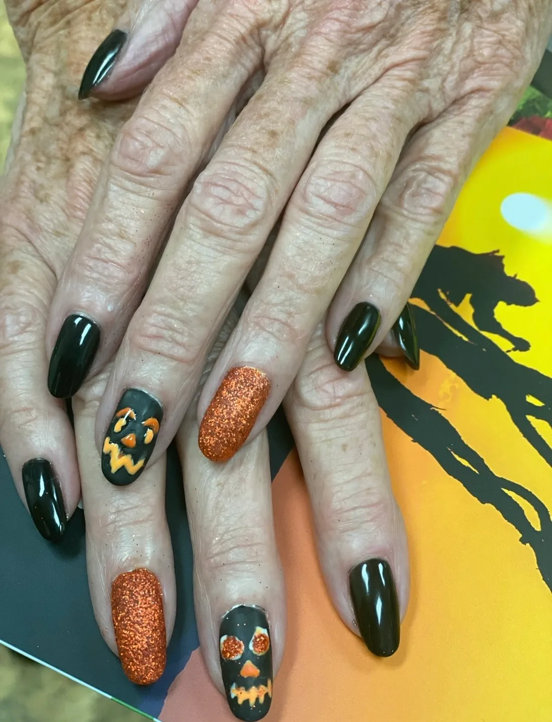 A woman 's nails with halloween designs on them.